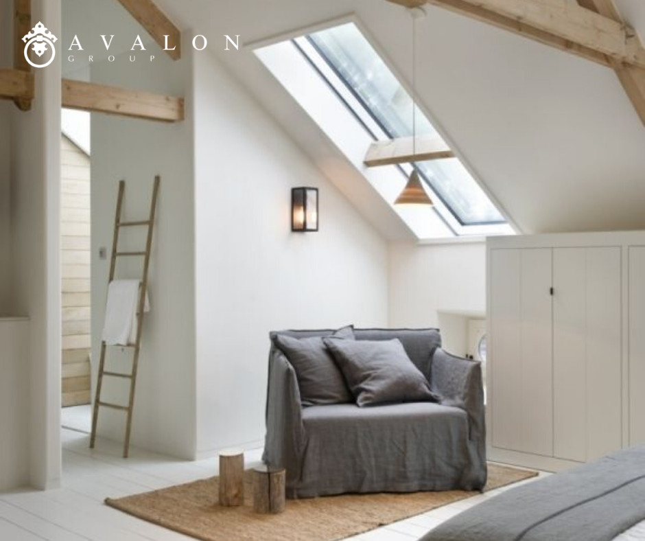 Furthermore, the pictures shows an attic remodel with a skylight in the slanted ceiling. Also, under the skylight is a large chair that is covered in a linen gray fabric.