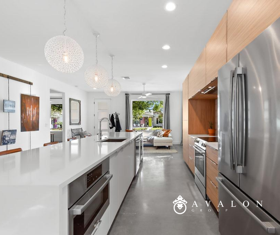 Also there is a white kitchen island with white quartz countertop. Additionally, the cabinets are a light brown wood finish.