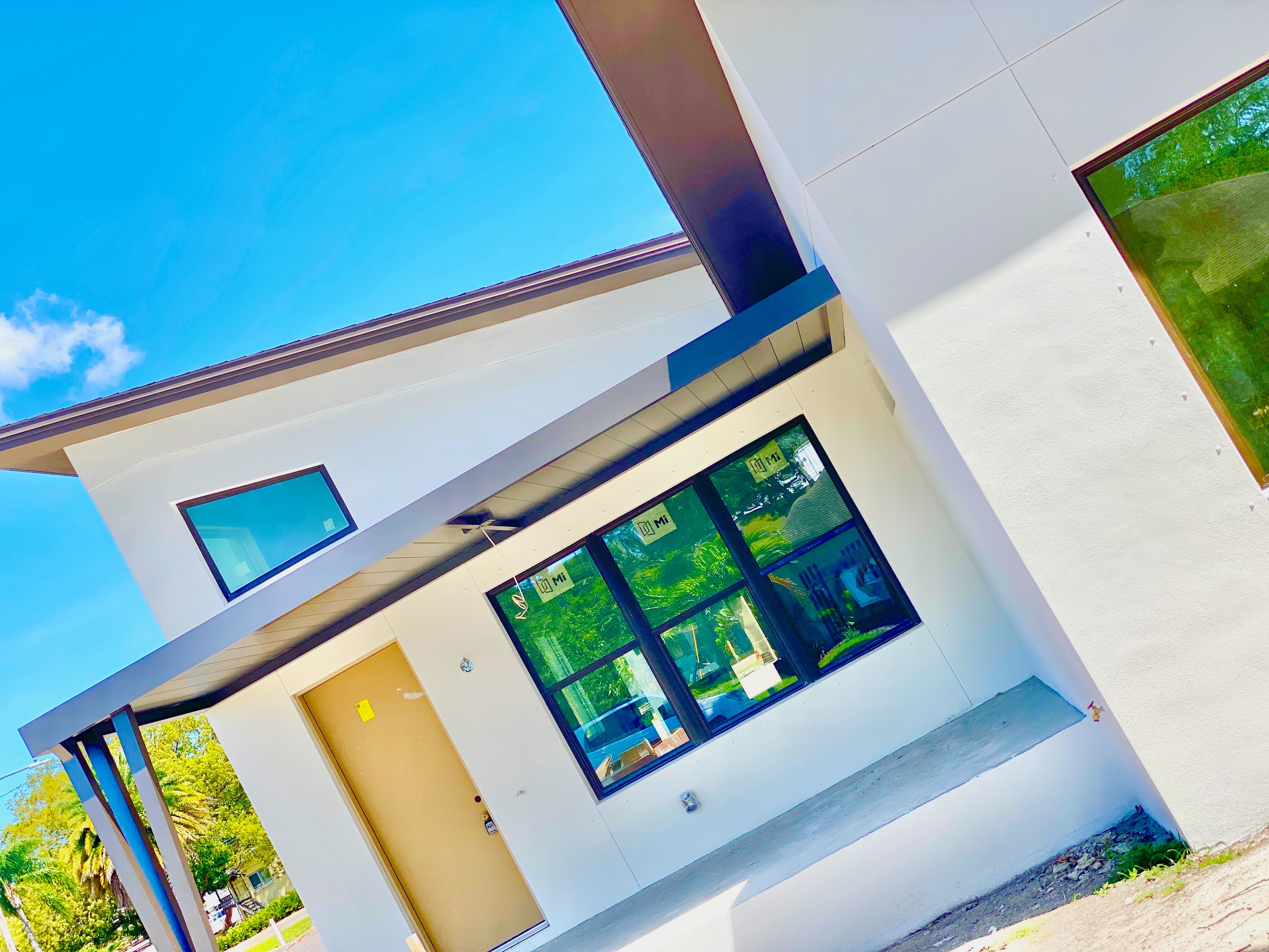 Also, this home is white with black trim. In addition, there is a large porch with a black metal flat roof.