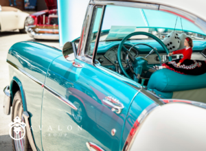 A photo of a classic car that is painted teal and white with chrome accents.