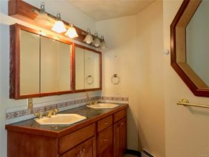 Double sink vanity in room with white walls and porthole window