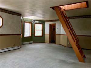 Gray carpeted room with a pull-down ladder leading up