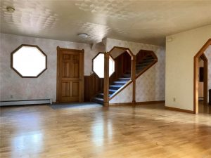 Expansive wood floor in open room with view of stairs leading up