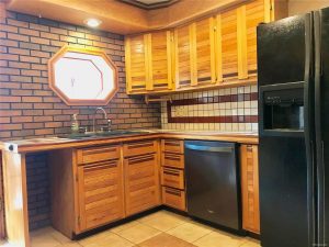 Custom wood cabinets in kitchen with porthole window and brick and tile details