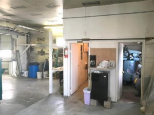 Garage interior showing partly open area, and also the entrances to the bathroom and the machinery room - there's a coffeemaker and mini fridge sitting between the two rooms