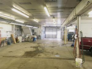 Interior garage with concrete floor and fluorescent lights; view shows light coming through garage door