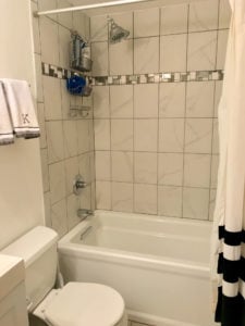 Bright white bathroom with commode and tub/shower