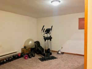 Carpeted room with stair-step machine and line of free weights