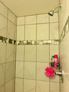 Inside of shower with white tiles that match the tiles in the main-floor bathroom