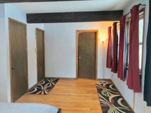 Bedroom with wood floors, three doors, and red curtains