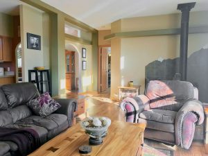 Bright living room with oversize sofa and chair, wood stove in background
