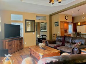 Bright living room with oversize sofa, big wooden coffee table and large flatscreen TV on a stand